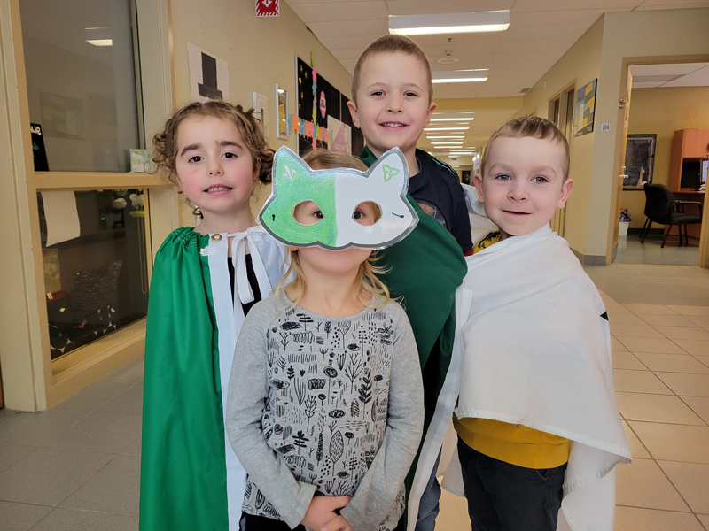 Des jeunes élèves portent plusieurs symbole de la francophonie ontarienne une d'entre eux porte un masque vert et blanc avec les symbole de la francophonie ontarienne