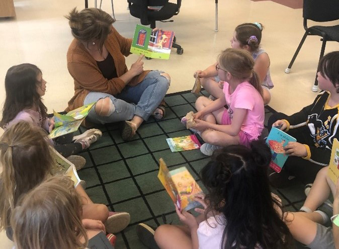 L'enseignante assit sur un tapis lis à ces élèves