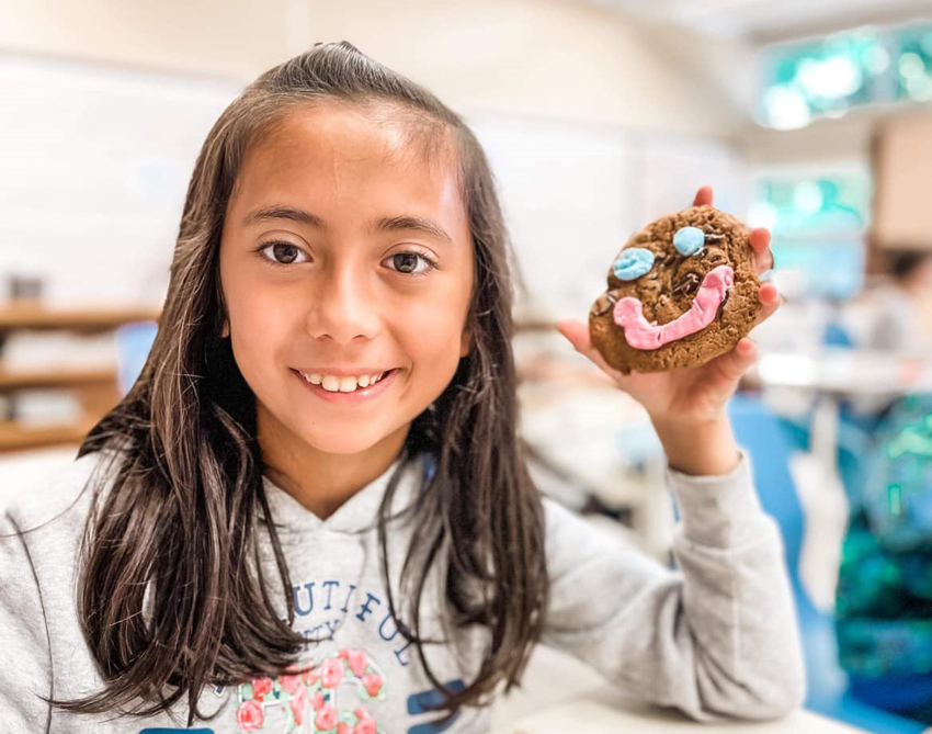 Une élèves avec un biscuit qui possède sourire dans la mains