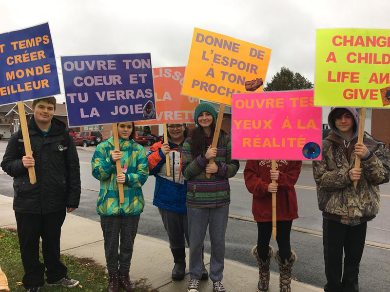 Étudiant qui proteste pour l'environnement avec différente pancartes.