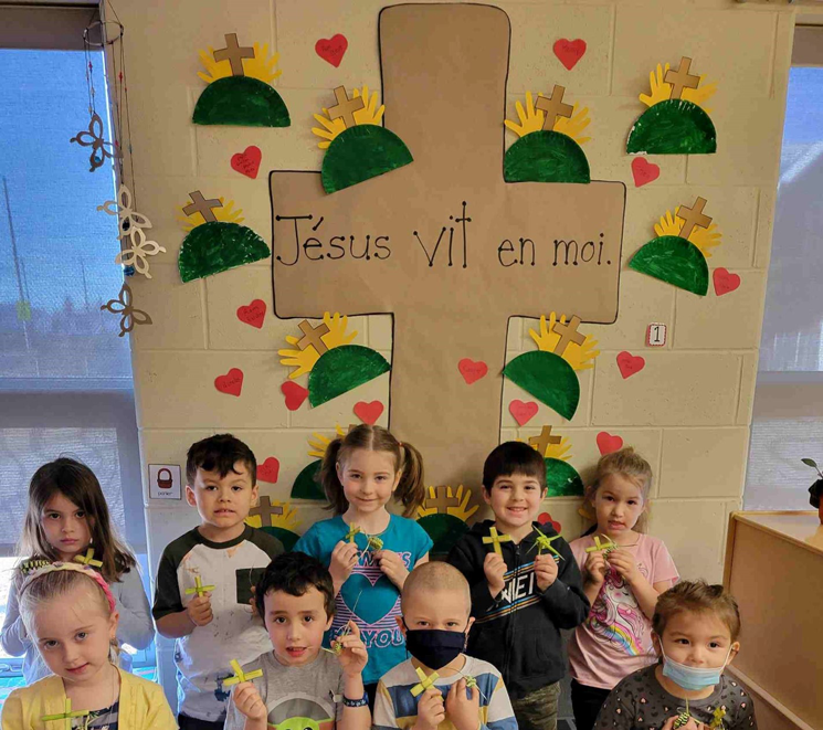 Un groupe d'élève pose avec leur crois devant une crois de carton sur lequel est écrit Jésus vit en moi