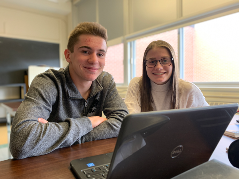 Deux étudiants devant un ordinateur portable sourit à la caméra