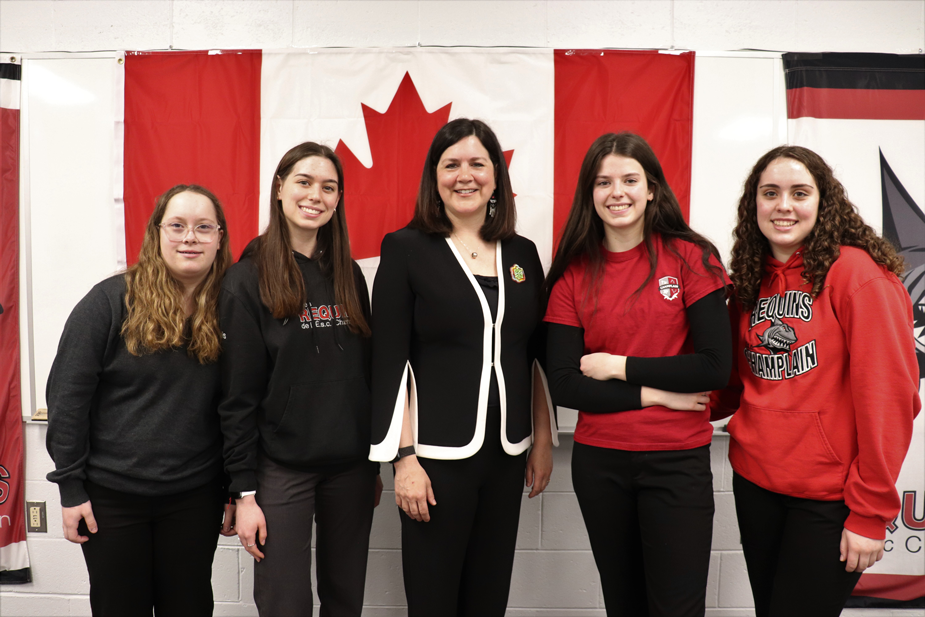 L'honorable Michelle O'Bonsawin avec des étudiantes devant le drapeau du Canada
