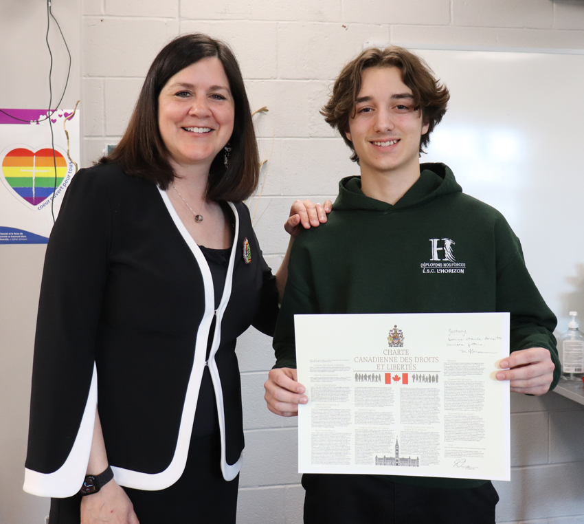 Un étudiant tien la charte canadienne des droits et liberté avec L'honorable Michelle O'Bonsawin
