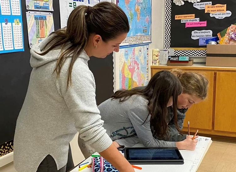 Des élèves font leurs devoir avec l'aide de leur étudiantes