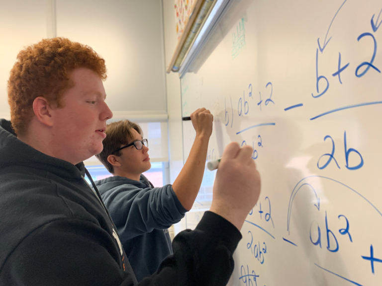 Deux étudiants résout un problème de math sur un tableau blanc