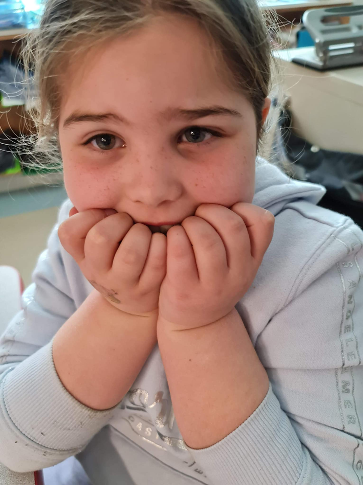 Une petite fille anxieuse avec les mains dans la bouche se mordant les doigts