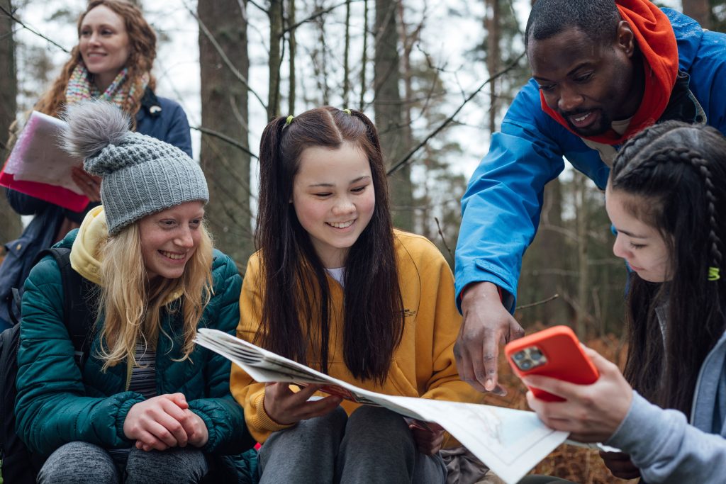 Un groupe d'élève dans la forest regarde une carte avec l'aide de leur enseignant
