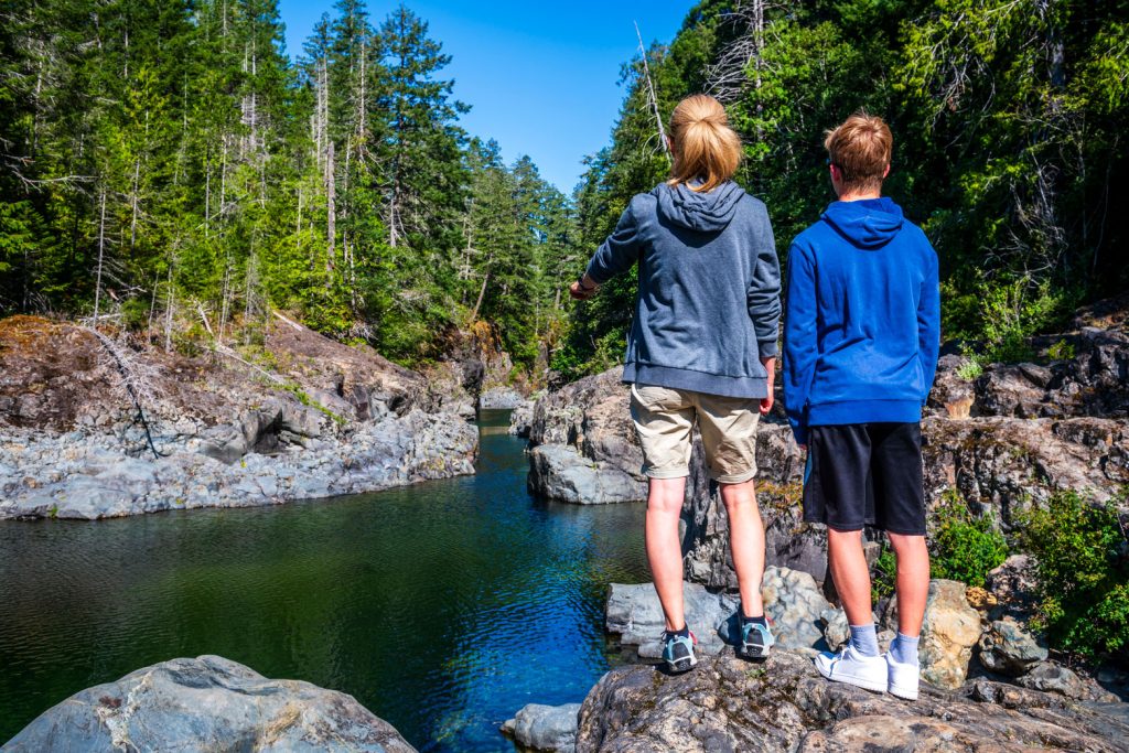 Deux jeunes ado sur une marche en pleine air regarde l'eau et la forêt